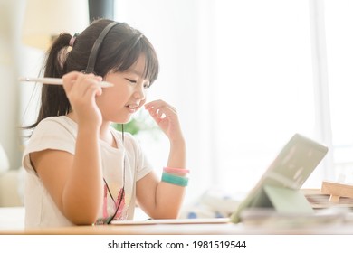 Asian Girl Student Online Learning At Home.study Online Video Call Zoom Teacher, Kid Girl Learn English Language Online With Tablet.