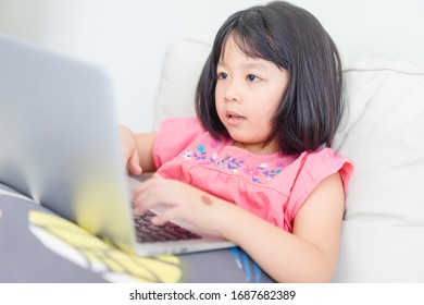 Asian Girl Student Study Online At Home With Video Call To Teacher And Friends, Happy Young Girl Learn English Language Listen And Learning Coding App Look At Laptop At Home.Covid-19 Coronavirus.