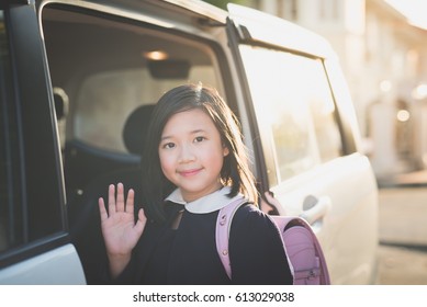 Asian Girl In Student Uniform Going To School By Car And  Waving Goodbye