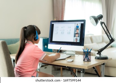 Asian girl student video conference e-learning with teacher and classmates on computer in living room at home. Homeschooling and distance learning ,online ,education and internet. - Shutterstock ID 1697599144