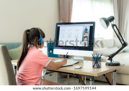 Asian girl student video conference e-learning with teacher and classmates on computer in living room at home. Homeschooling and distance learning ,online ,education and internet.