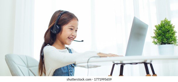 Asian girl student wear headphone study online with video call teacher, Happy young girl learn english language listen lecture watch write notes look at laptop at home.Covid-19 coronavirus. - Powered by Shutterstock