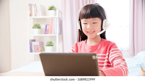 Asian Girl Student Wear Headset Microphone And Use Tablet Pc To Have Online Language Class Happily At Home