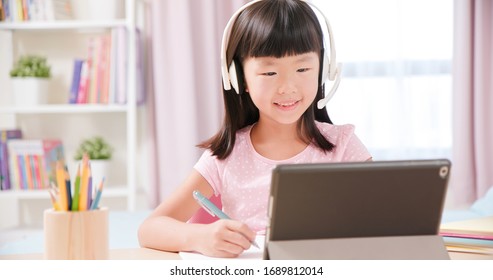 Asian Girl Student Wear Headset Microphone And Use Tablet Pc To Have Online Language Class Happily At Home