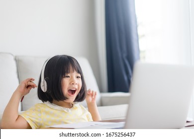 Asiatische Mädchen Schüler tragen drahtlose Kopfhörer-Studie online mit Video-Call-Lehrer, Happy junge Mädchen lernen englische Sprache hören Vorlesungen Schreib-Noten auf Laptop zu Hause.Covid-19 coronavirus.