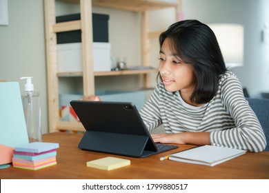 Asian Girl Is Studying Online Via The Internet On Tablet Digital While Sitting At The Table At Night. Concept Of Online Learning At Home