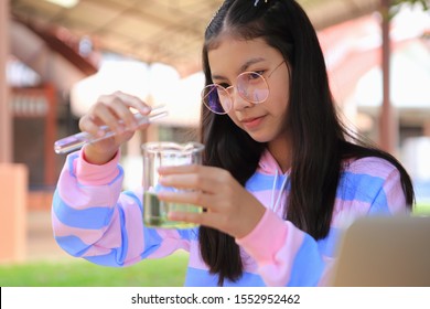 An Asian girl is studying science. She is observing the chemical changes.