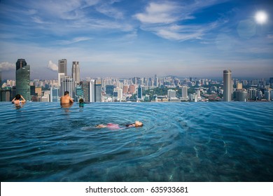 Asian girl swim in swimming pool on the roof top of hotel in Singapore city, Singapore and summer concept
