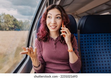 an Asian girl talks amiably with a client or friend on the phone during a country trip on a modern high-speed train - Shutterstock ID 2231021693