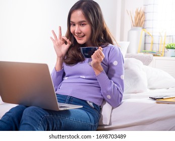 Asian Girl Uses A Laptop To Talk Through Video Conferencing In The House. Require Friends To Spend Time Together During Holidays And Social Distance. Stay Home Happy