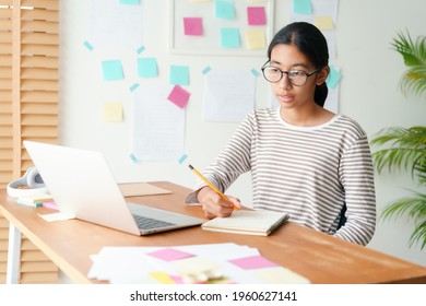 Asian Girl Video Call Online Via The Internet Tutor On Computer Laptop. Asia Student Women Wear Glasses Doing Homework In The Morning And Sunlight. Concept Online Learning At Home