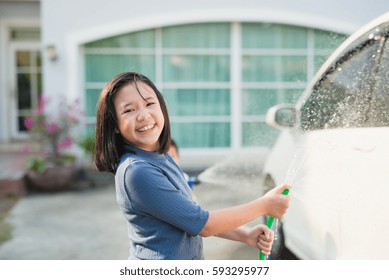 Asian girl washing car in the garden on summer day - Powered by Shutterstock