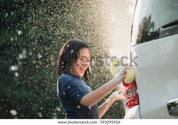 Asian girl
washing car in the garden on summer
day