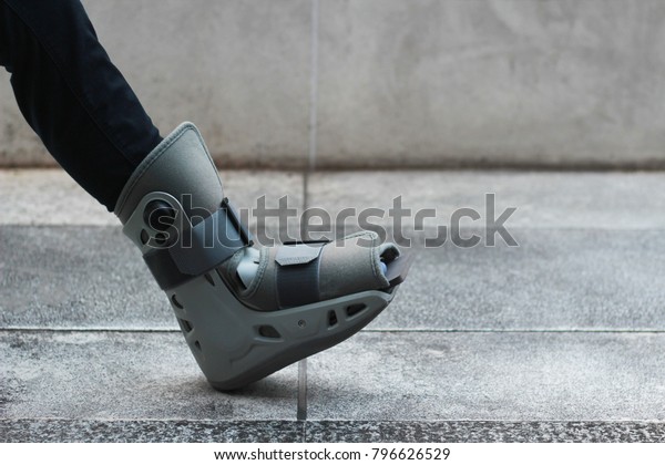 A Asian girl is wearing the ankle support boot\
after surgery.