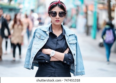 Asian Girl Wearing Blue Jean Jacket, Sun Glasses And Red Headband Walking On Street With Blurred Background, Asian Girl Street Fashion Portrait