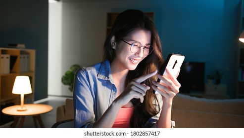 asian girl wearing eyeglasses use smart phone happily at home in the evening