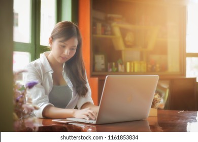 Asian girl wearing a white shirt playing a tablet in a cafe in the morning - Shutterstock ID 1161853834