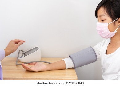 Asian Girl Wearing A White T-shirt Wearing A Mask Is Measuring Blood Pressure.