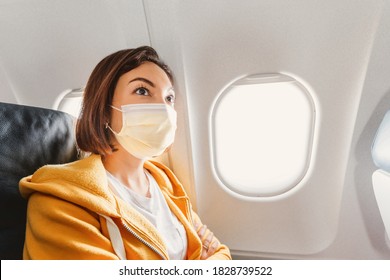 An Asian Girl Wears A Medical Face Mask During An Airplane Flight. Concept Of Safety And New Rules Of Conduct For Air Transport Passengers