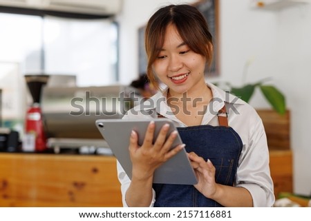 Asian girl, Young Portrait of an Asian beautiful smiling female starting small business owner with tablet near a counter in her cafe.
