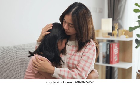 Asian girls comforting her crying sister, hugging her, and whispering words of support, closeup. Asian girls embrace female kid, touching her head, and saying something - Powered by Shutterstock