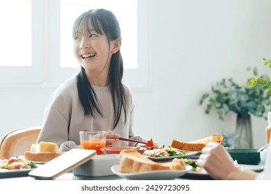 Asian girls enjoy eating around the dining table. - Powered by Shutterstock