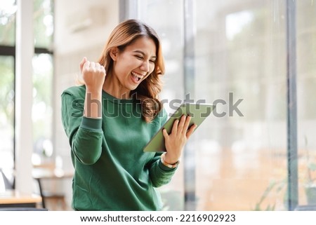 Asian girls are excited about victory. hand holding a digital tablet at her office