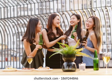 Asian Girls gang drinking beer while enjoying rooftop bar party. Group of friends having fun at terrace party.Concept about women night out.
