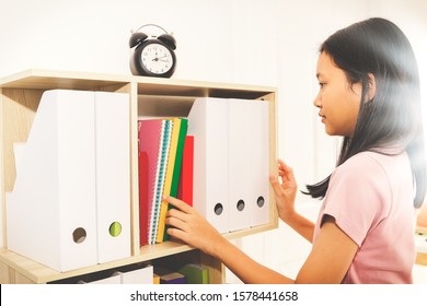 Asian Girls Intend To Organize The Documents And Textbooks To Be Organized On The Bookshelf In The Classroom : Side View
