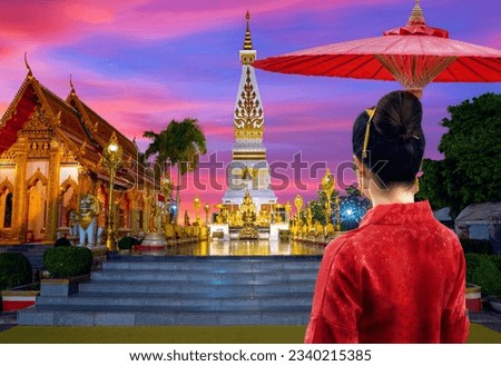 Asian girls in Lanna Thai dress visit Phra That Phanom Pagoda at dusk in Nakhon Phanom province, Thailand.