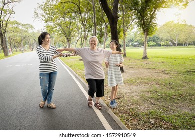 Asian Granddaughter,daughter Assisting Senior Mother To Walking Follow White Line On The Floor With The Support At Park, Female Elderly Try To Balance With Arms Open,testing And Risk Fall Prevention