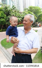 Asian Grandfather Holding Grandson And Walking In The Garden