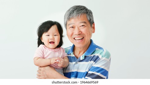 Asian Grandfather Hug His Baby Toddler Granddaughter And Smiling At You Happily With White Background