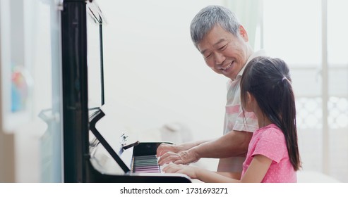 asian grandfather teach girl playing the piano happily