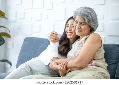 Asian Grandma And Granddaughter Hugged With Happy Mood On The Sofa In Home.