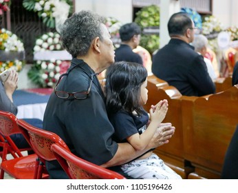 Asian Grandmother Holding Her Granddaughter And Paying Respect To The Death And Listening To Buddhist Monk Chanting At Traditional Thai Funeral - Child Development By Doing/imitating What Adults Do