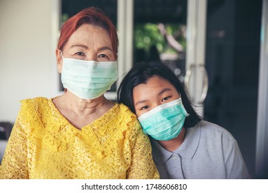 Asian Grandmother And Kid Wear Mask And Playing Together. Thai Elderly Woman And Child Greeting And Hug At Home. Happy Family Concept.