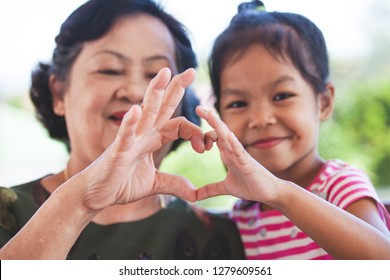 Asian Grandmother And Little Child Girl Making Heart Shape With Hands Together With Love