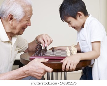 Asian Grandpa And Grandson Playing Chess.