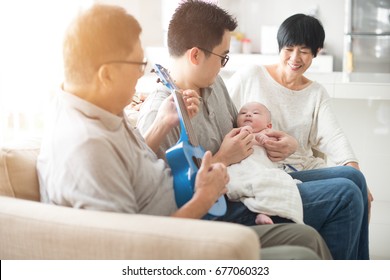 Asian Grandparent Playing Music With Father And Baby Indoor