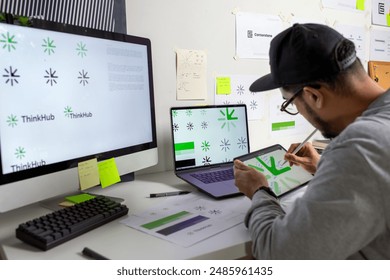 Asian graphic designer making notes on logo designs, using Tablet, designing logos, and showcasing the corporate identity and logo design process. - Powered by Shutterstock