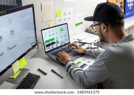 Asian graphic designer making notes on logo designs, using computers, designing logos, and showcasing the corporate identity and logo design process.	