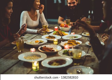 Asian Group Eating And Drinking Cold Beer Outside The House At Night, Having Fun Talking