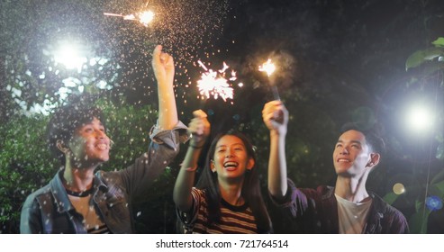 Asian Group Of Friends Having Outdoor Garden Barbecue Laughing With Alcoholic Beer Drinks And Showing Group Of Friends Having Fun With Sparklers On Night ,soft Focus