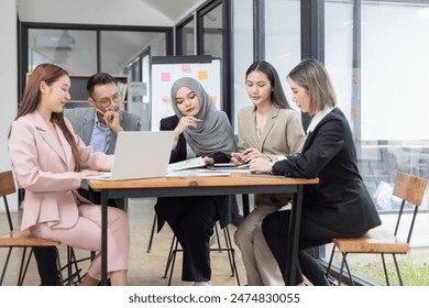 Asian group of people working with documents have financial or marketing charts on a board room table at a business presentation or seminar, business training meeting concept.  - Powered by Shutterstock