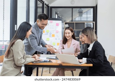 Asian group of people working with documents have financial or marketing charts on a board room table at a business presentation or seminar, business training meeting concept.  - Powered by Shutterstock