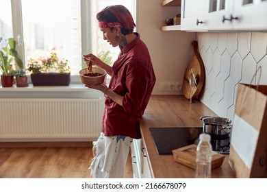 Asian Guy Standing In The Kitchen And Eating Noodles With Chopsticks