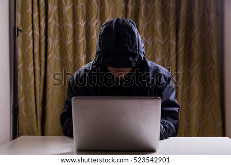Asian hacker hacking computer network with laptop in dark