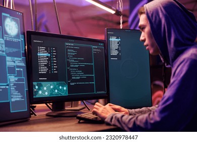 Asian hacker using ransomware to attack server and cracking password. Internet scammer in hood planning phishing attack and developing malicious software to breach data in dark room