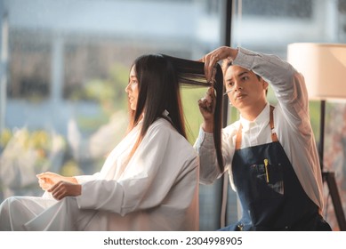 Asian Hairdresser giving treatment and barber occupation service, Professional hairstylist combing and using scissors cut woman's hair to young beautiful customer girl in beauty salon - Powered by Shutterstock